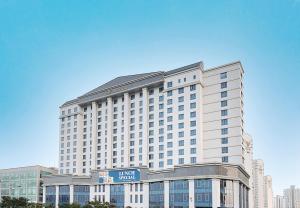 a large white building with a sign in front of it at Osong H Hotel Sejong City in Cheongju