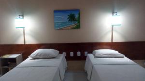 two beds in a room with two lights on the wall at Delta Park Hotel in Parnaíba
