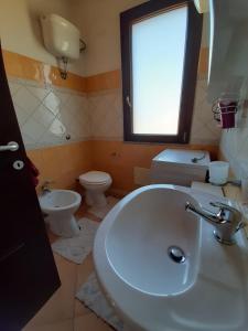 uma casa de banho com um lavatório, um WC e uma janela. em Vacanze da Macandu & Stefi em San Giovanni Suergiu