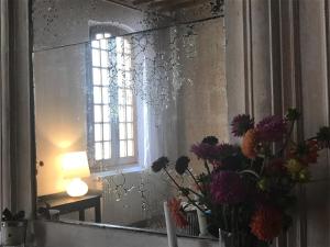 un miroir avec un vase de fleurs et une fenêtre dans l'établissement Le Patio d'Arles, à Arles