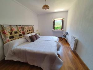 a bedroom with a large white bed in a room at Casa Rural O Rabadan in Cedeira