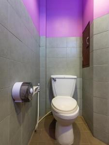 a bathroom with a toilet and a purple wall at OYO 1127 Baan Siam Hotel in Chiang Rai