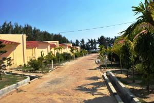 曼塔莫尼的住宿－Resort Hirak Jayanti，一条土路,两旁有房子和棕榈树
