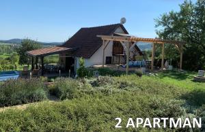 a house with a pergola in the yard at Pécsely apartman in Pécsely