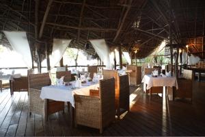 a restaurant with white tables and chairs and tablesearcher at Fundu Lagoon in Pemba