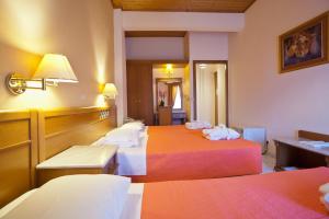 a hotel room with three beds and a table at Acropole Delphi City Hotel in Delphi