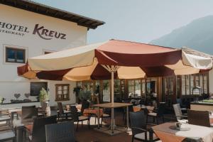 un restaurante con mesas y sillas y una sombrilla grande en Hotel Kreuz, en Pfunds