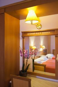 a hotel room with a bed and a lamp and flowers at Acropole Delphi City Hotel in Delphi