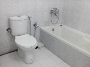 a bathroom with a white toilet and a bath tub at Neel Nirjaney Resorts in Mandarmoni