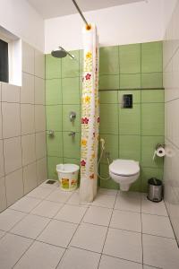 baño verde con aseo y ducha en Vasudevam Premium Suites en Thiruvananthapuram