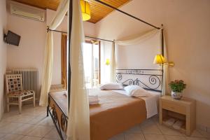 1 dormitorio con cama con dosel y ventana en Acropole Delphi City Hotel en Delfos