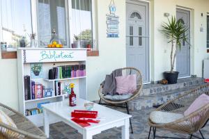 een veranda met stoelen, een tafel en een boekenplank bij Vila Primavera in Vama Veche