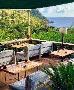 a patio with wooden tables and chairs and the ocean at Turan Hill Lounge in Faralya