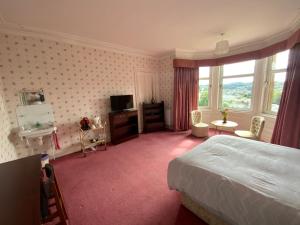 una camera d'albergo con letto, TV e finestra di Dunrigh Guest House a Oban Altre 24 foto