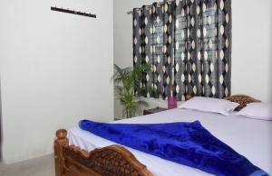 a bedroom with a bed with a blue blanket on it at Coorg peacock feathers home stay in Kushālnagar