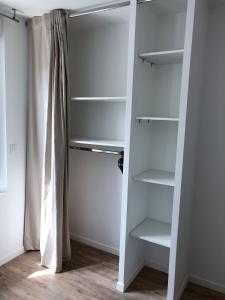 a walk in closet with white shelves and a curtain at Appartement 6pers spacieux et fonctionnel in Saumur