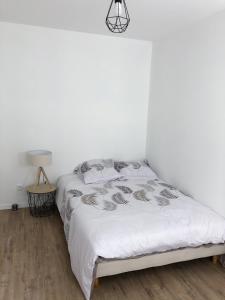 a bedroom with a bed with white sheets and a lamp at Appartement 6pers spacieux et fonctionnel in Saumur