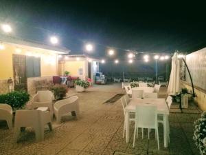 un patio con mesas blancas, sillas y luces en Garden Inn, en Capua