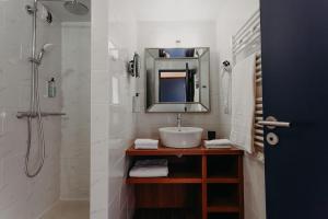 a bathroom with a sink and a shower with a mirror at Baya Hotel in Capbreton