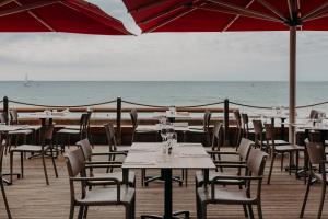a beach area with tables, chairs and umbrellas at Baya Hotel in Capbreton