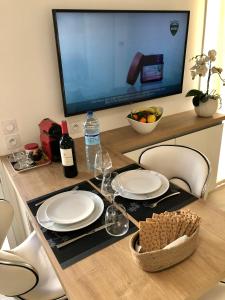 a table with plates and wine glasses and a television at Brand new studio in the heart of Cannes in Cannes