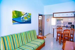 uma sala de estar com um sofá e uma cozinha em Bungalows Los Almendros - Exclusive Vacation Club em Playa del Inglés