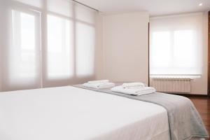 a white bedroom with a large white bed with windows at Casa peñasBLANCAS en Duruelo de la sierra Soria 12personas in Duruelo de la Sierra