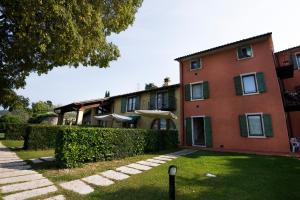 ein großes rotes Gebäude mit einer Hecke davor in der Unterkunft Residence Corte Camaldoli in Garda