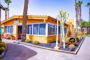 a yellow house with palm trees in front of it at Bungalows Los Almendros - Exclusive Vacation Club in Playa del Ingles