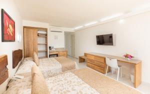 a hotel room with two beds and a desk and a television at Posada Real Puerto Escondido in Puerto Escondido