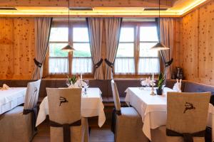 ティローロにあるHotel Hoferのテーブル2台と椅子、窓のあるレストラン