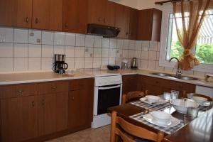 eine Küche mit Holzschränken, einem Tisch und einer Spüle in der Unterkunft Garden's Villa in Leptokaryá