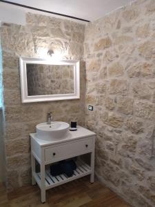 baño con lavabo y pared de piedra en Casa di Carmine 1915 - Solo Adulti, en Gamberale