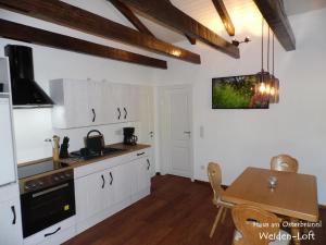 eine Küche mit weißen Schränken und einem Holztisch mit einem Esszimmer in der Unterkunft Haus am Osterbrünnl in Ruhmannsfelden