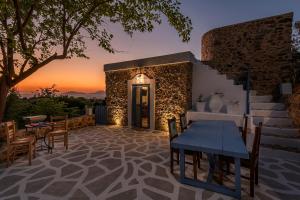 a patio with a table and chairs and a sunset at The Aegean blue country house Old Milos in Lagoúdi Zía