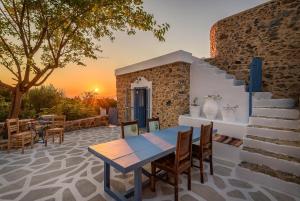 einen Tisch und Stühle auf einer Terrasse mit Blick auf den Sonnenuntergang in der Unterkunft The Aegean blue country house Old Milos in Lagoúdi Zía