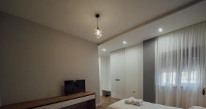 Schlafzimmer mit einem Bett, einem TV und einem Fenster in der Unterkunft Guesthouse Sara & Esi in Korçë