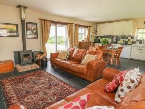 a living room with a leather couch and a fireplace at Blaenffynnon Bach in Carmarthen