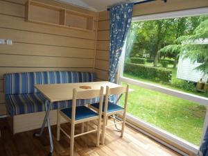 stół i krzesła w pokoju z oknem w obiekcie camping du ried à proximité d'Europa-Park et Rulentica w mieście Boofzheim