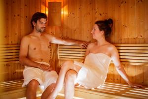 Ein Mann und eine Frau sitzen in einer Sauna in der Unterkunft Hotel-Restaurant Allmer in Weiz