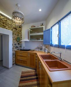 a kitchen with wooden cabinets and a sink and a chandelier at The Aegean blue country house Old Milos in Lagoúdi Zía