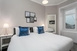 a bedroom with a large white bed with blue pillows at Seaforth Suite - Donnini Apartments in Ayr
