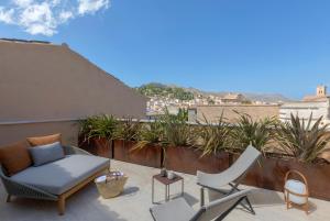 d'une terrasse avec un canapé et des chaises sur un balcon. dans l'établissement Can Aulí Luxury Retreat - Adults Only, à Pollença
