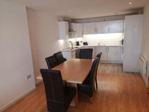 格拉斯哥的住宿－Glasgow Central Riverview Luxury Apartment (Sleeps upto 8)，厨房以及带木桌和椅子的用餐室。