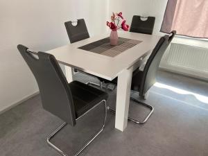 uma mesa branca com cadeiras pretas e um vaso com flores em Aachener Ferienwohnung em Aachen