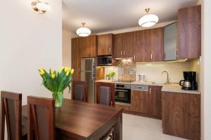 a kitchen with wooden cabinets and a vase of flowers on a table at Vanilla 7 Apartment in Kraków