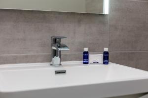 a bathroom sink with a faucet and two bottles on it at Seaforth Suite - Donnini Apartments in Ayr