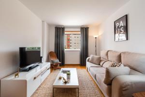uma sala de estar com um sofá e uma televisão em Conchas - 88214AL em Lisboa