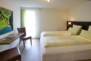 ein Hotelzimmer mit 2 Betten, einem Schreibtisch und einem Stuhl in der Unterkunft Hotel Rhodannenberg AG in Glarus
