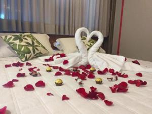 two white swans sitting on a bed covered in roses at Pitaya Apart Hotel in Garopaba